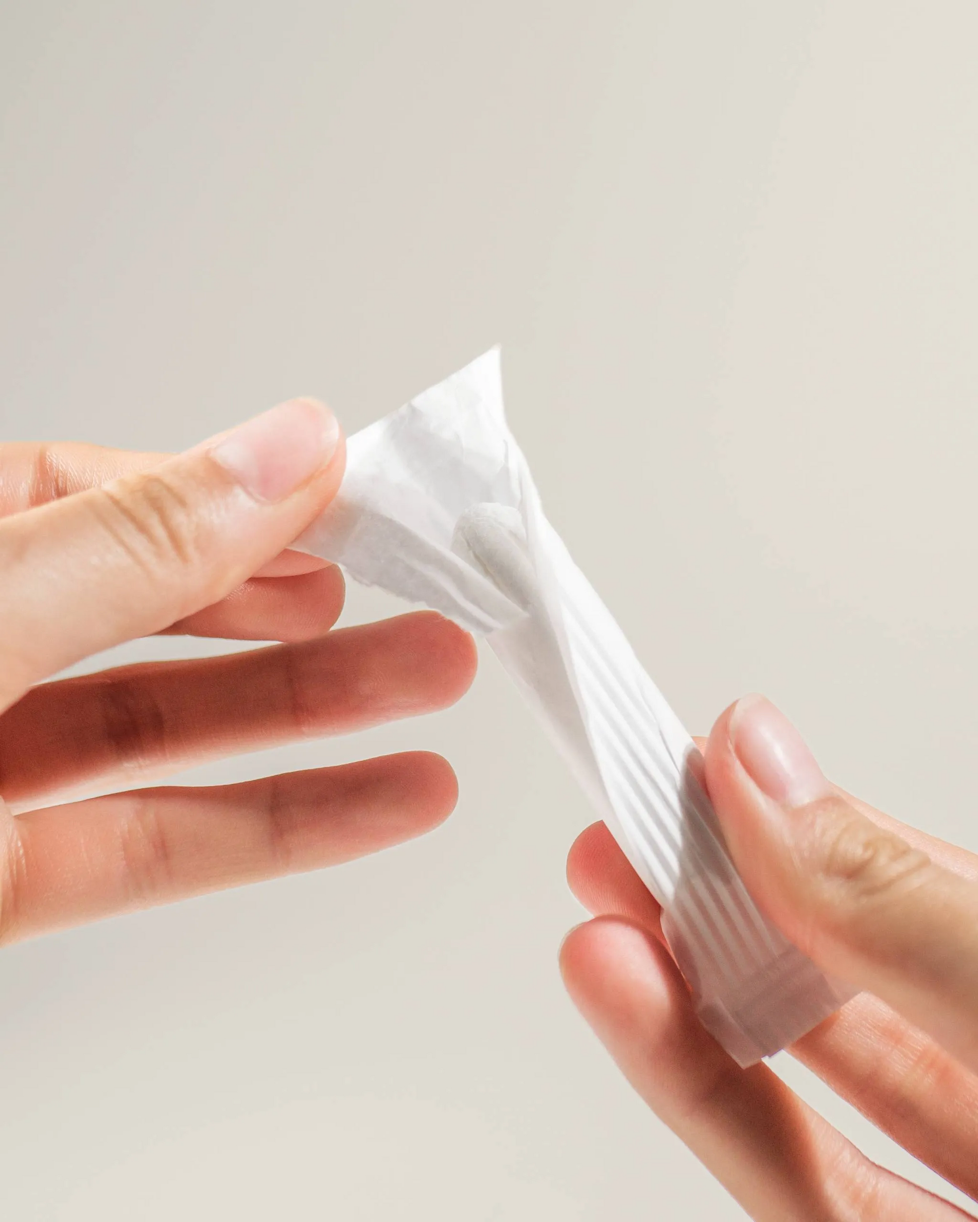 Image of hands unwrapping organic cotton non-applicator tampon